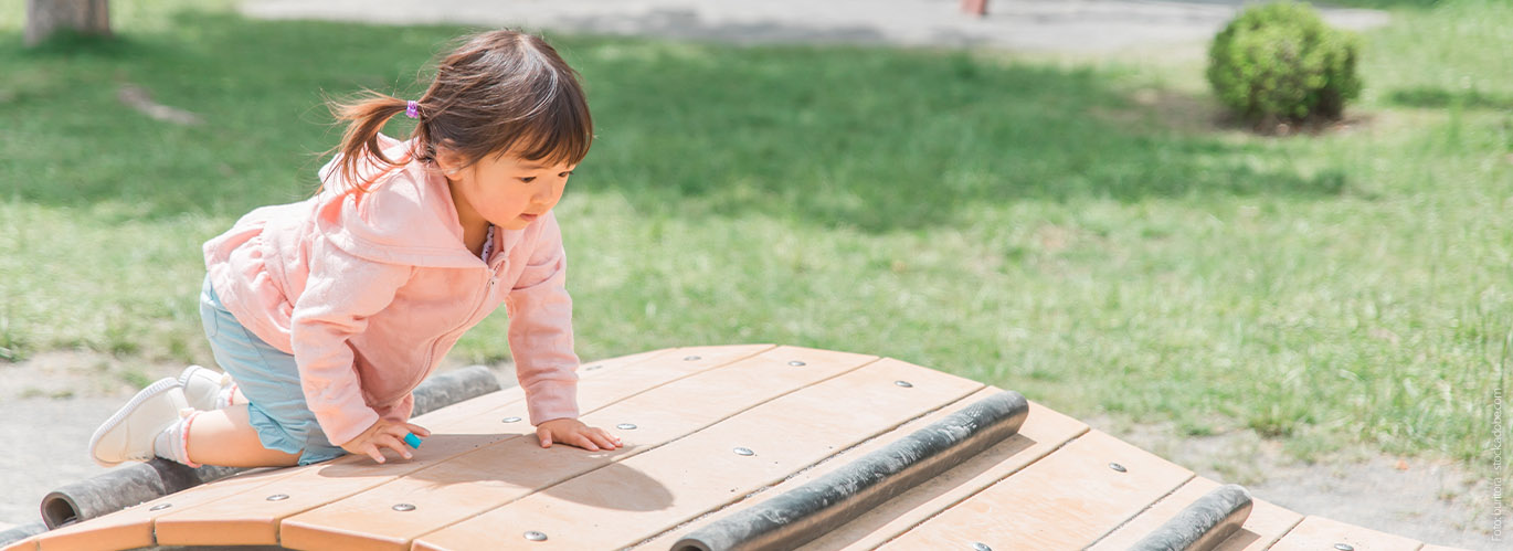 Kleinkind in Bewegung Mädchen klettert auf Spielplatz